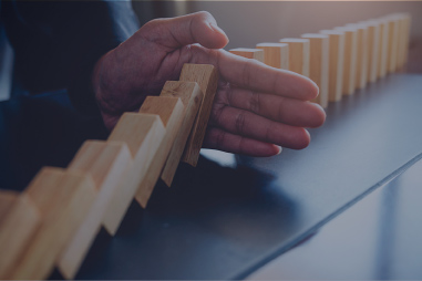 Hand stopping a line of dominoes.